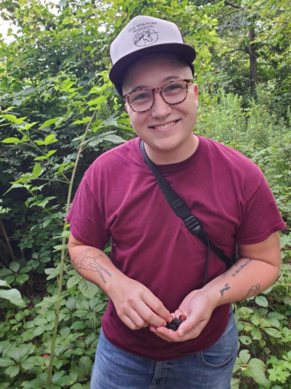 A portrait of Eden in woods with a handful of berries.