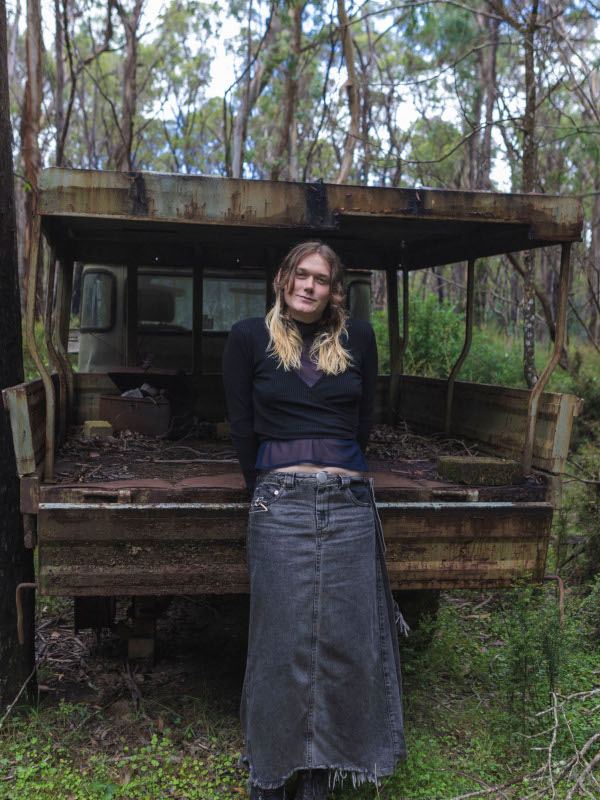 A portrait of Willow, also in the woods, perched on an old truck.